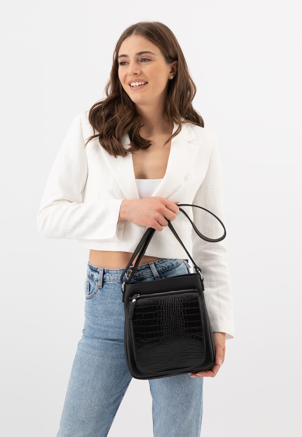 Czarna skórzana listonoszka damska Wojas model 80076-51 z eleganckim krokodylim wzorem, prezentowana na ramieniu modelki w białej marynarce i jeansach.