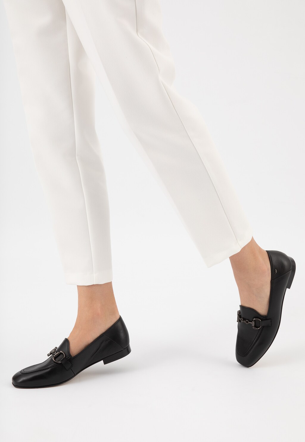 Czarne skórzane półbuty damskie Wojas 46224-51 z elegancką metalową ozdobą, noszone do białych spodni, widok z boku pokazujący klasyczny, elegancki design.