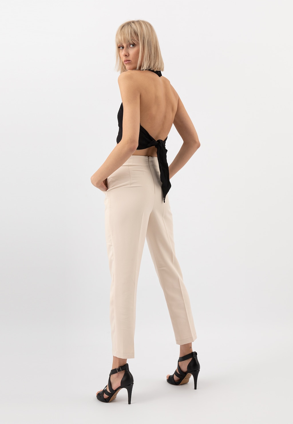 Eleganckie czarne sandały damskie Wojas model 76045-51 na szpilce prezentowane przez modelkę w jasnych spodniach i bluzce z odkrytymi plecami, widok z profilu.