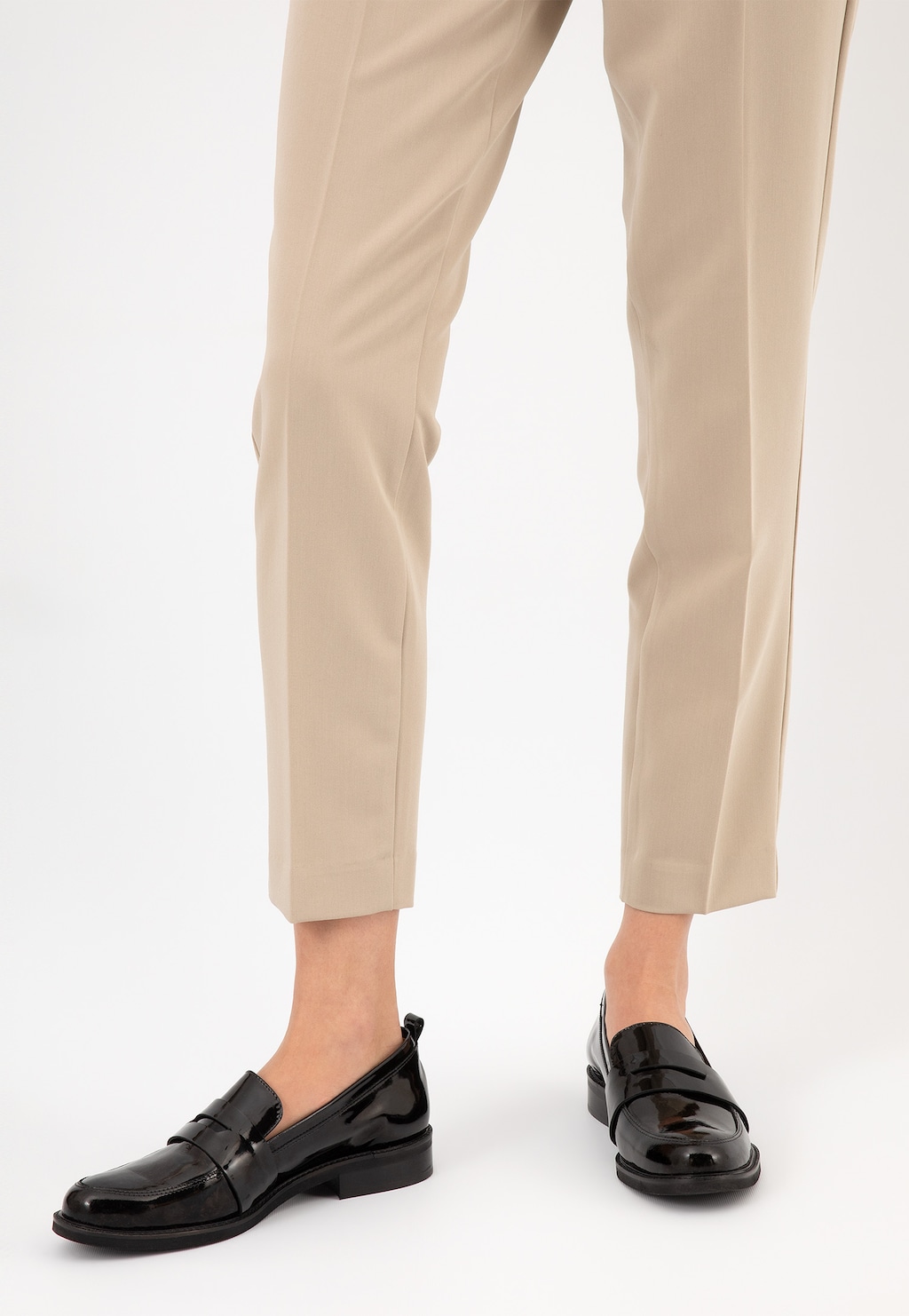 Eleganckie czarne lakierowane mokasyny damskie Wojas model 46069-31 zaprezentowane na nogach w beżowych spodniach, widok z przodu, idealne do stylizacji formalnych.