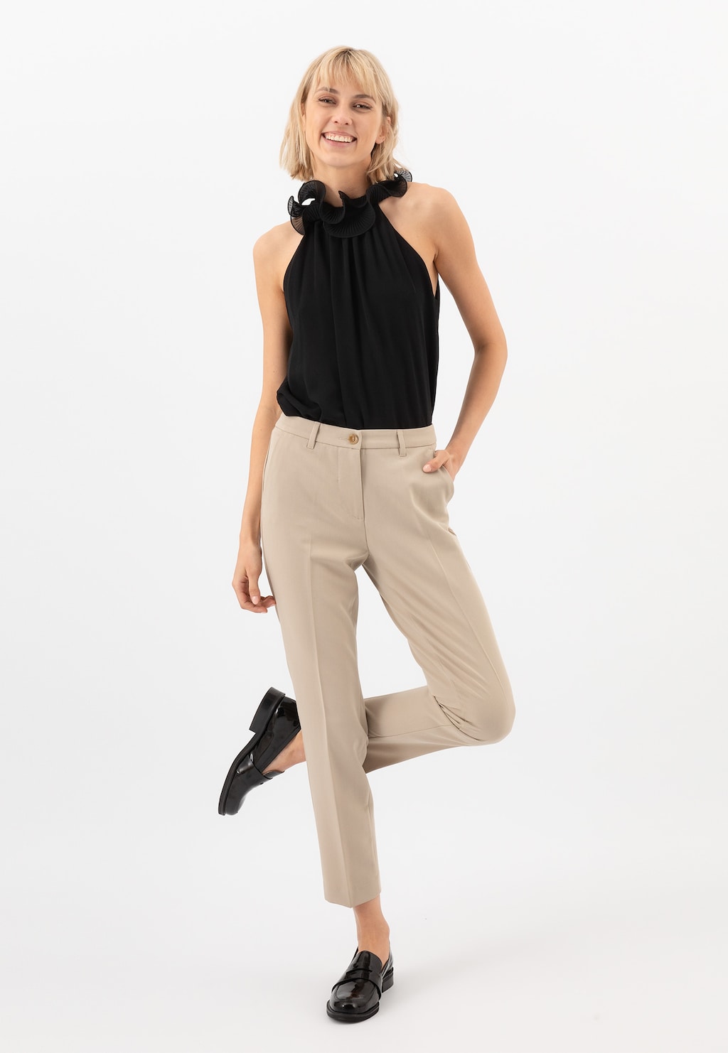 Elegancki strój biznesowy z czarną bluzką z wysokim kołnierzem i beżowymi spodniami, uzupełniony czarnymi lakierowanymi mokasynami Wojas model 46069-31 w stylu formal.