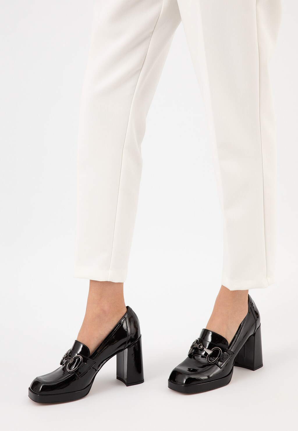 Eleganckie czarne lakierowane mokasyny damskie Wojas 46216-31 na grubym słupku, prezentowane na nogach modelki w białych spodniach, widok z profilu.