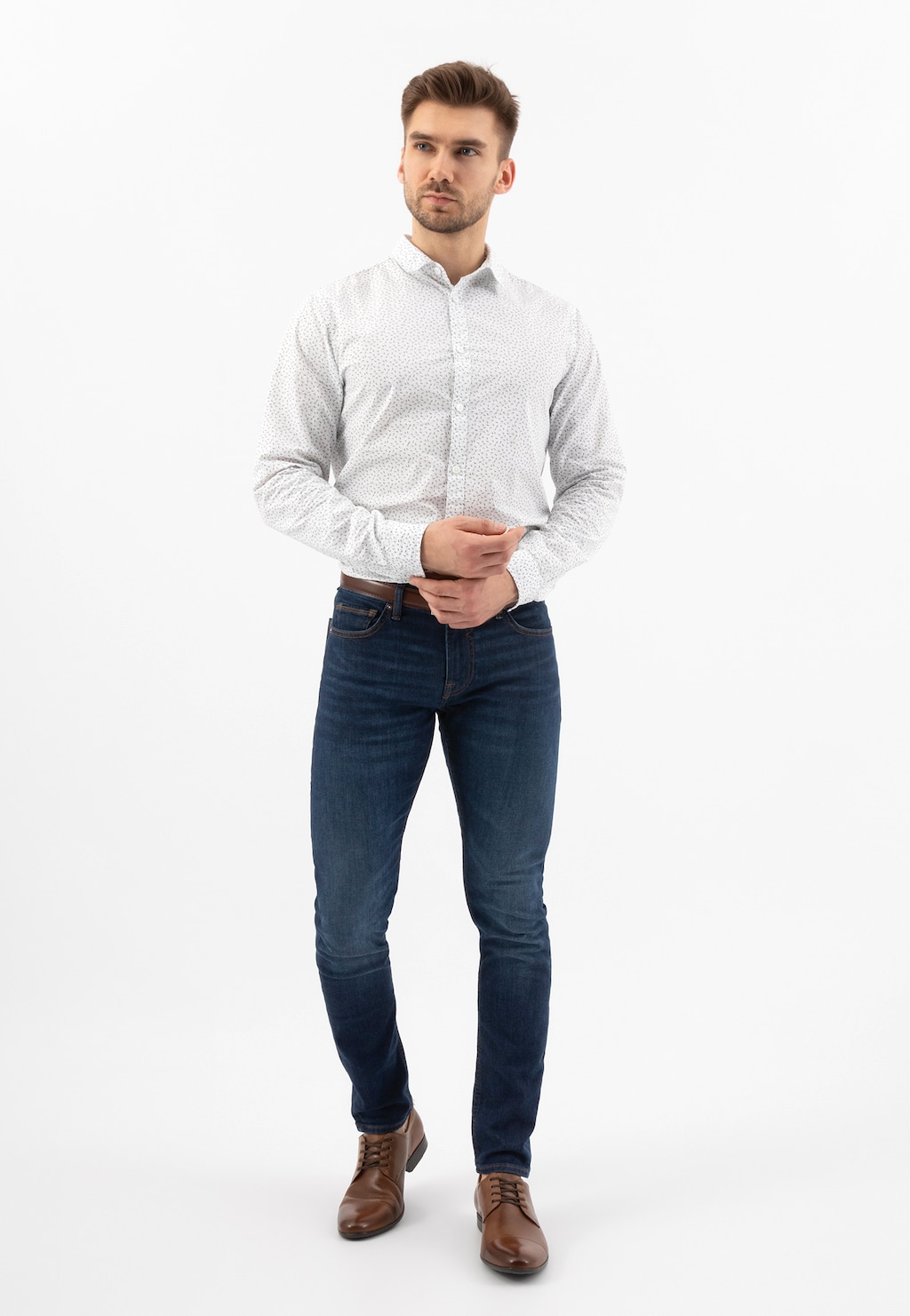 Model w białej koszuli i granatowych jeansach prezentuje brązowe eleganckie półbuty męskie Wojas model 9036-52, ukazane z przodu w pełnej stylizacji biznesowej.