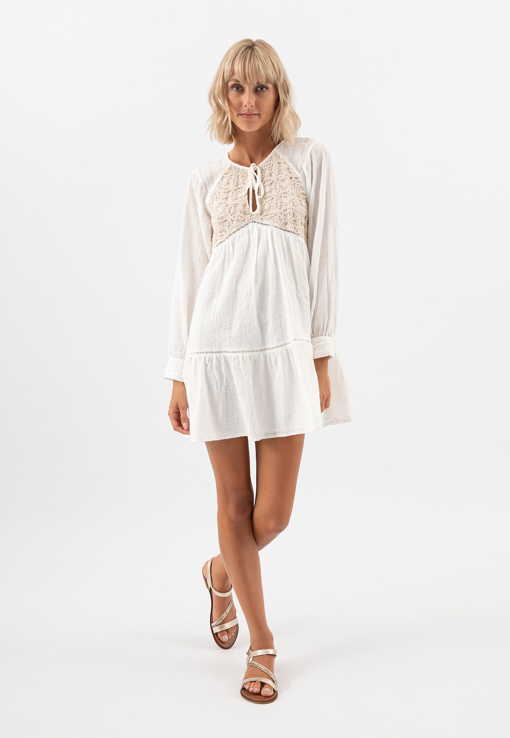 Modelka w białej sukience boho prezentuje złote sandały damskie Wojas model 76048-58 na płaskiej podeszwie, idealne na lato.