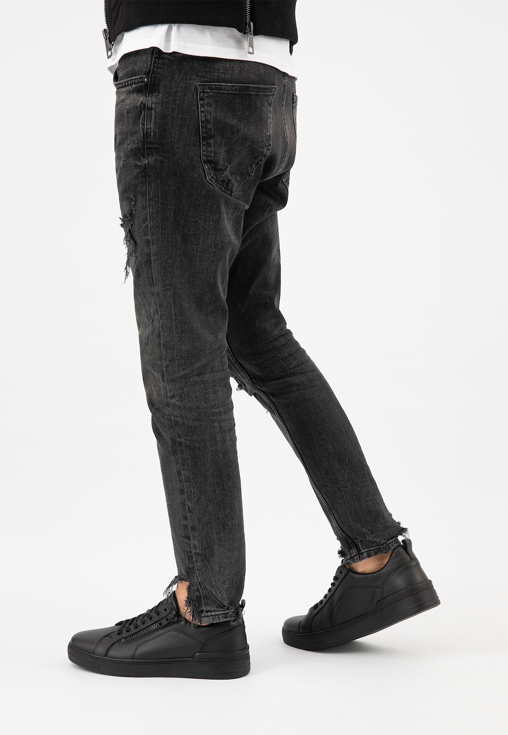 Czarne trampki Wojas 10149-51 ze skóry licowej z zamkiem na cholewce, prezentowane na modelu w ciemnych jeansach z przetarciami i czarną górną częścią ubioru.