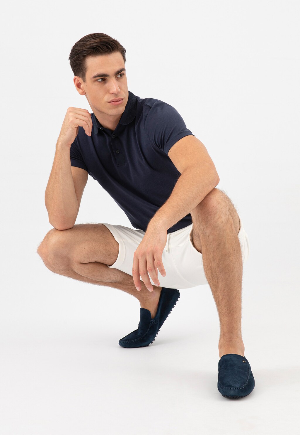 Model w granatowej koszulce polo i jasnych szortach prezentuje granatowe skórzane mokasyny męskie Wojas model 10145-66 typu car shoes w eleganckiej, casualowej stylizacji.