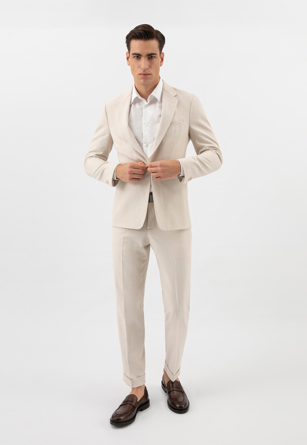 Model w jasnym garniturze prezentuje brązowe mokasyny męskie Wojas ze skóry licowej model 10137-52, idealne uzupełnienie eleganckiej stylizacji.