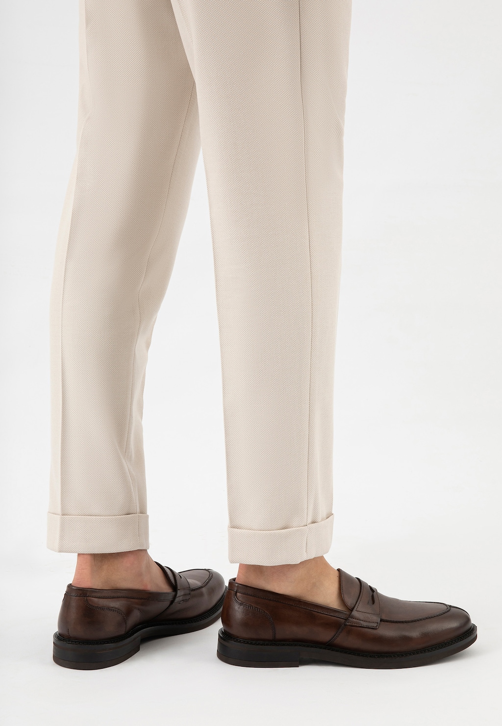 Eleganckie brązowe mokasyny męskie Wojas model 10137-52 ze skóry licowej, prezentowane na stopach mężczyzny ubranego w jasne spodnie z podwiniętymi nogawkami.