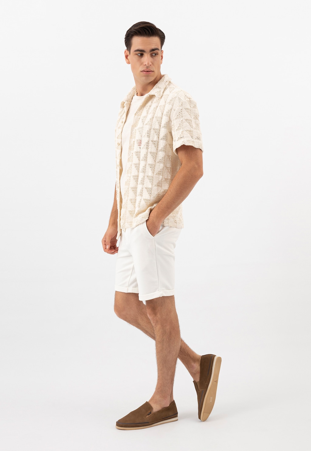 Model prezentuje beżowe wsuwane półbuty męskie Wojas 10113-24 z nubuku, nosząc kremową koszulę z wzorem i białe szorty w letniej stylizacji.