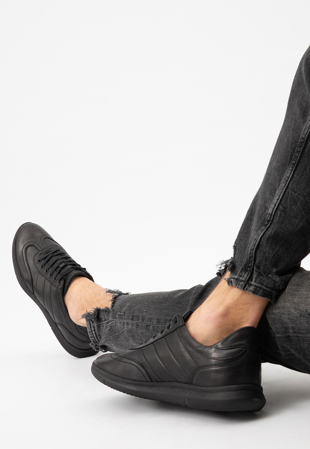 Czarne półbuty męskie Wojas 10038-51 ze skóry licowej w stylu comfort na nogach w ciemnych, podartych dżinsach, widok z boku pokazujący elegancki, sportowy charakter obuwia.