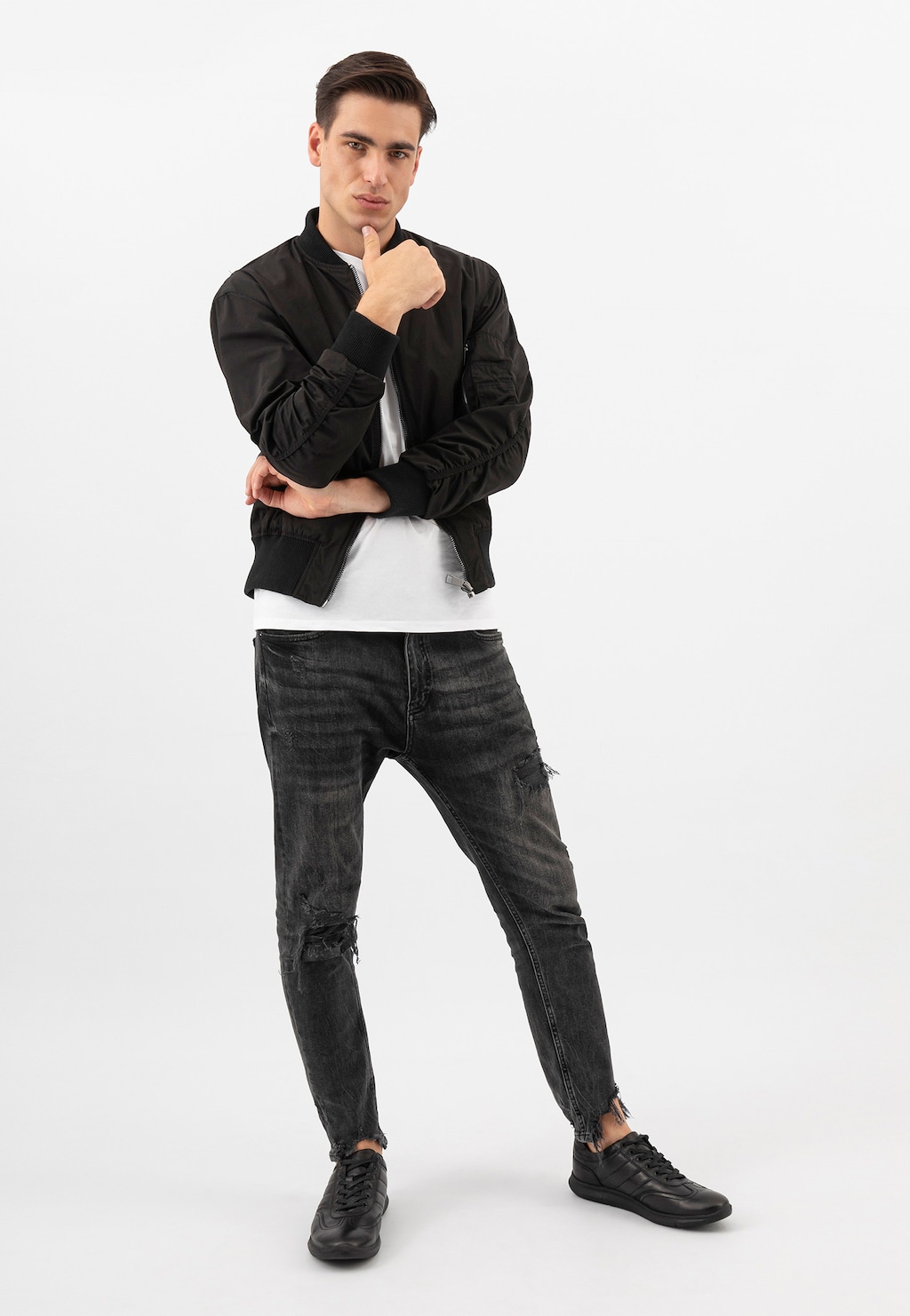 Model w czarnej kurtce i podartych jeansach prezentuje czarne półbuty męskie Wojas 10038-51 ze skóry licowej w stylu comfort, idealne do casualowych stylizacji.