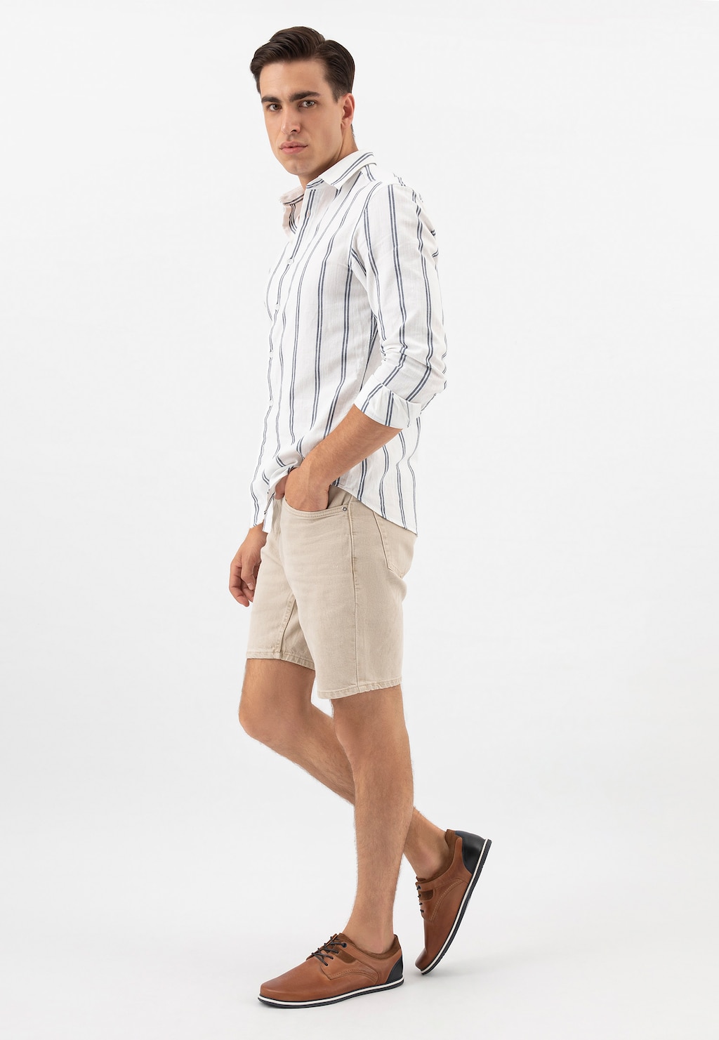 Model w letniej stylizacji prezentujący wygodne półbuty męskie Wojas 10027-73 z granatową wstawką. Brązowe buty idealnie uzupełniają zestaw z koszulą w paski i beżowymi szortami.