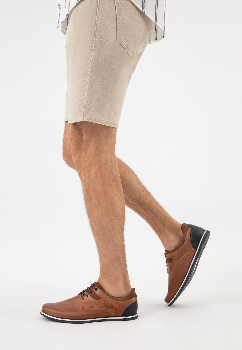 Eleganckie półbuty męskie Wojas model 10027-73 w brązowym kolorze z granatową wstawką, prezentowane na nodze mężczyzny w jasnych szortach, idealne do letnich stylizacji.