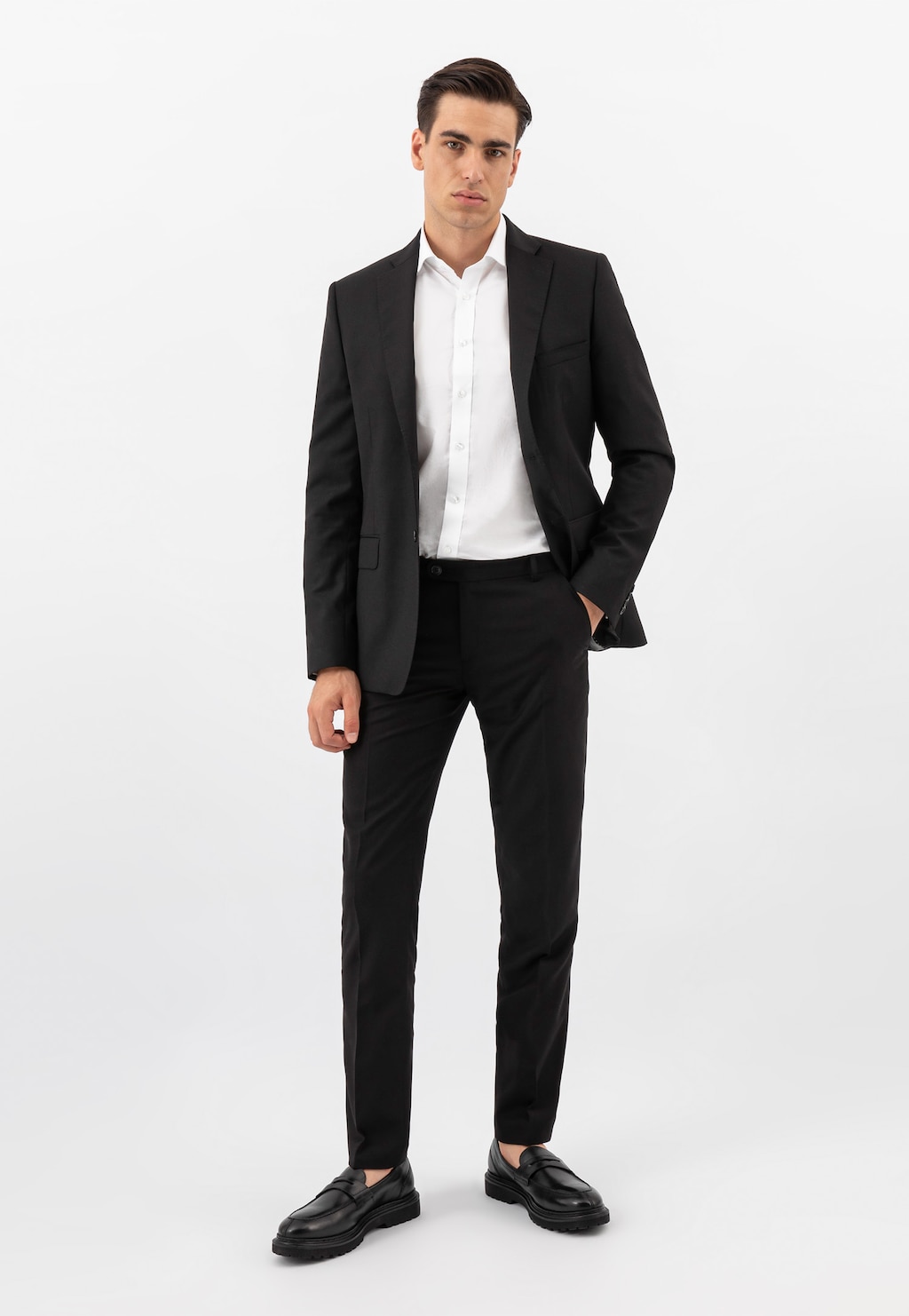 Model w eleganckim czarnym garniturze i białej koszuli prezentuje czarne mokasyny męskie Wojas ze skóry licowej, model 10138-51, idealne do stylizacji biznesowych.