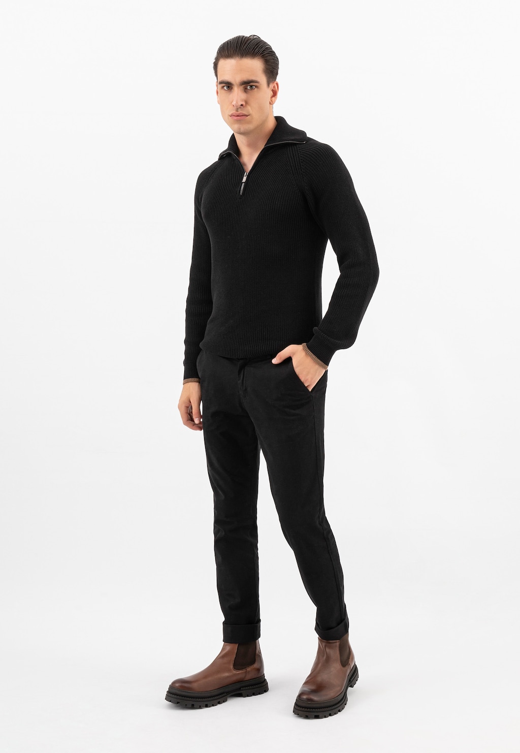 Model w czarnym swetrze z półgolfem i spodniach, prezentujący brązowe sztyblety męskie Wojas model 20018-52 z masywną podeszwą, w eleganckim casualowym zestawieniu.