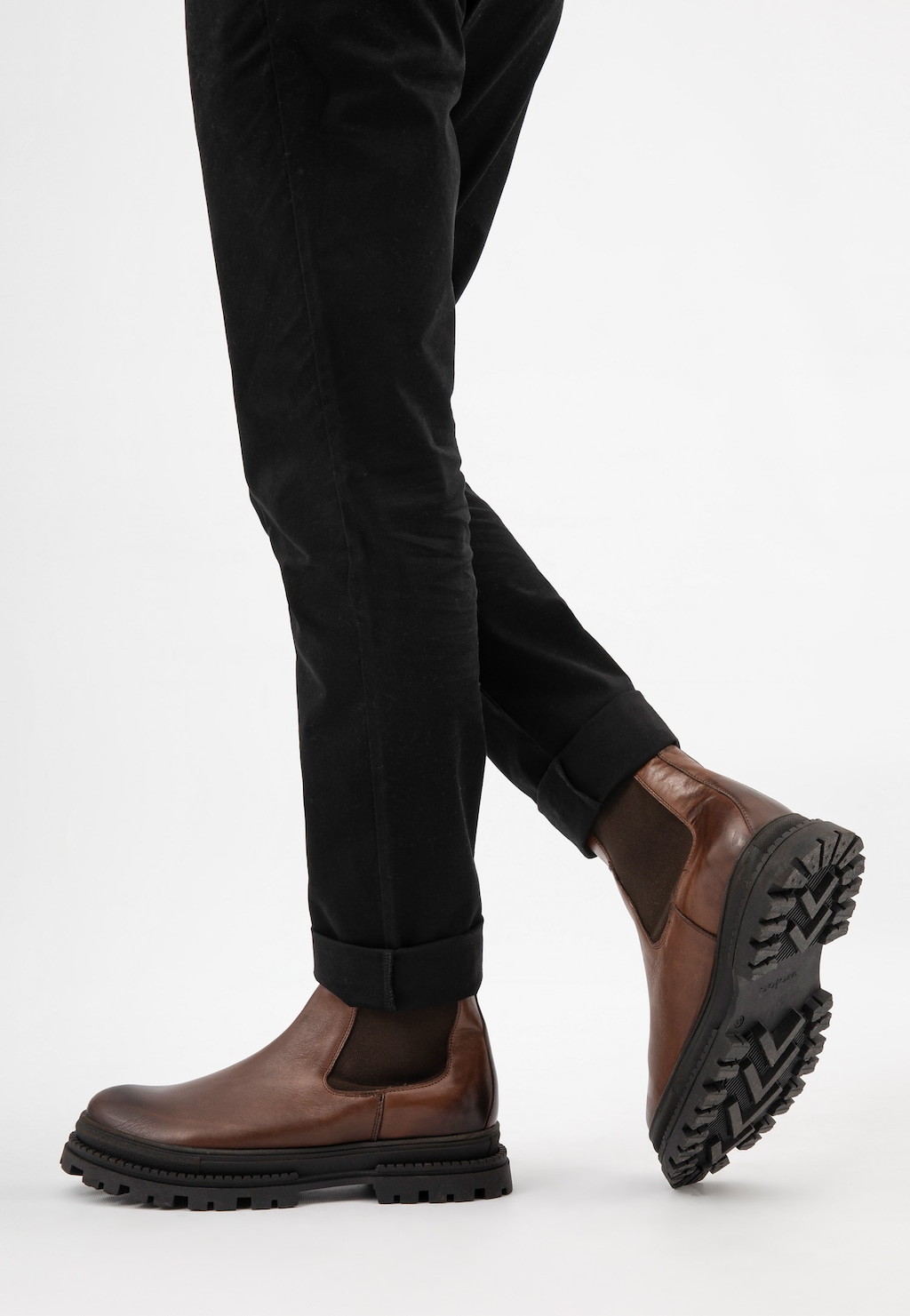 Brązowe skórzane sztyblety męskie Wojas model 20018-52 z grubą podeszwą, widoczne na nogach w czarnych spodniach. Stylowe buty z boczną gumką i wytrzymałym protektorem.