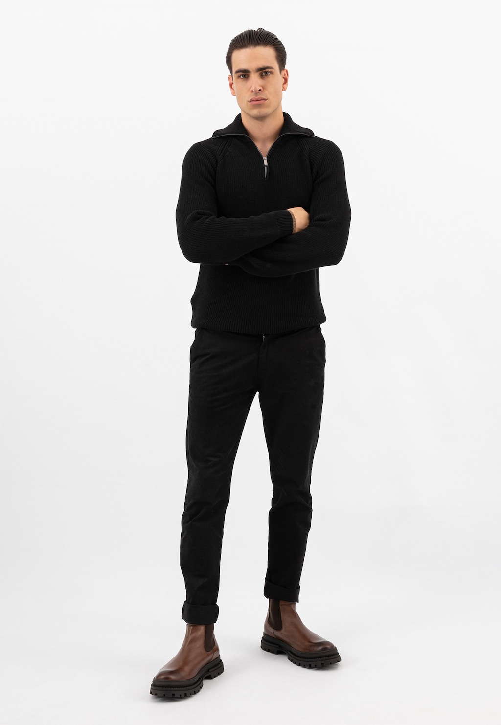 Model w eleganckim czarnym stroju prezentujący brązowe sztyblety męskie Wojas 20018-52. Całościowy widok stylizacji z wysokimi skórzanymi butami na masywnej podeszwie.