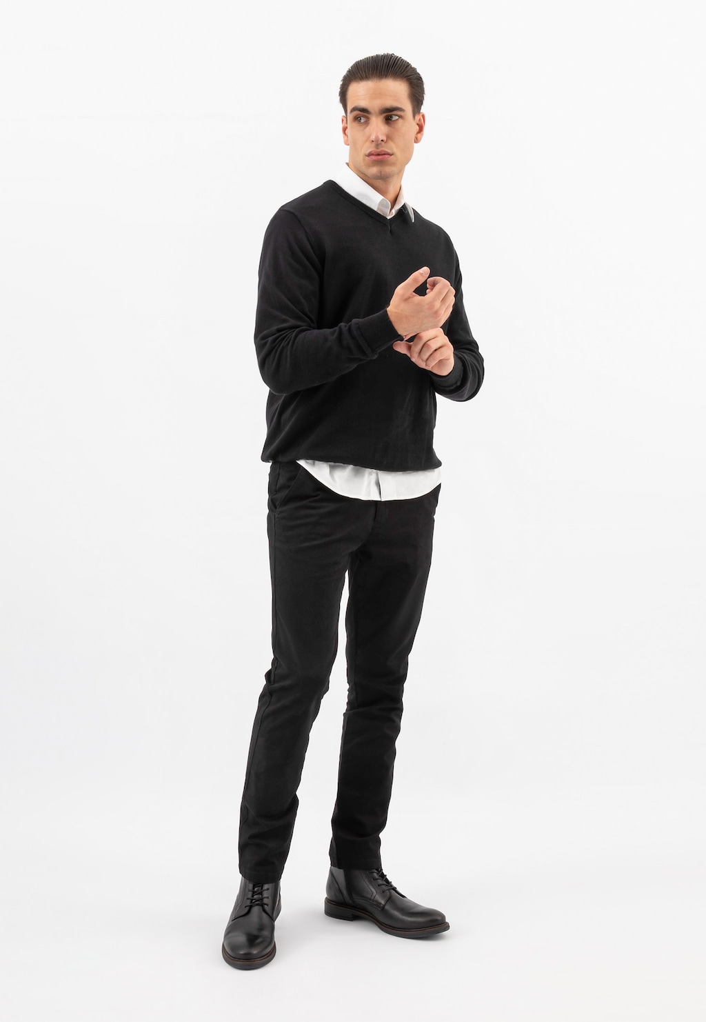 Model w eleganckim stroju prezentuje czarne klasyczne trzewiki męskie Wojas model 24052-51 ze skóry licowej, noszone ze spodniami i swetrem w czarnym kolorze.