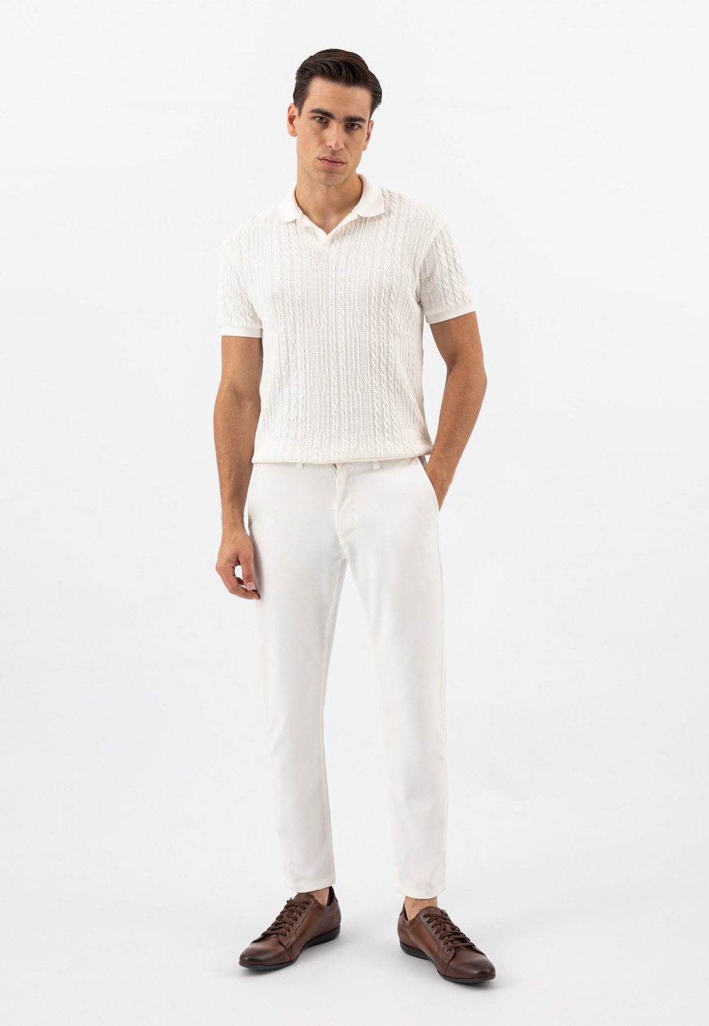 Model w białym komplecie prezentuje brązowe półbuty męskie Wojas model 7004-52. Eleganckie obuwie widoczne z przodu, idealne uzupełnienie stylizacji.