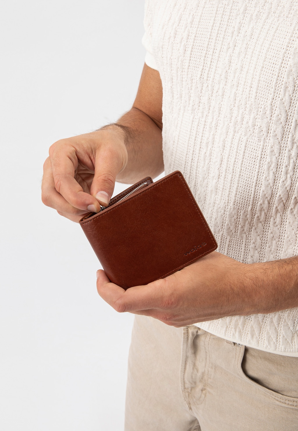 Jasnobrązowy skórzany portfel męski Wojas model 91072-53 trzymany w dłoniach przez mężczyznę w białym swetrze, prezentujący elegancki design produktu z zamkiem.