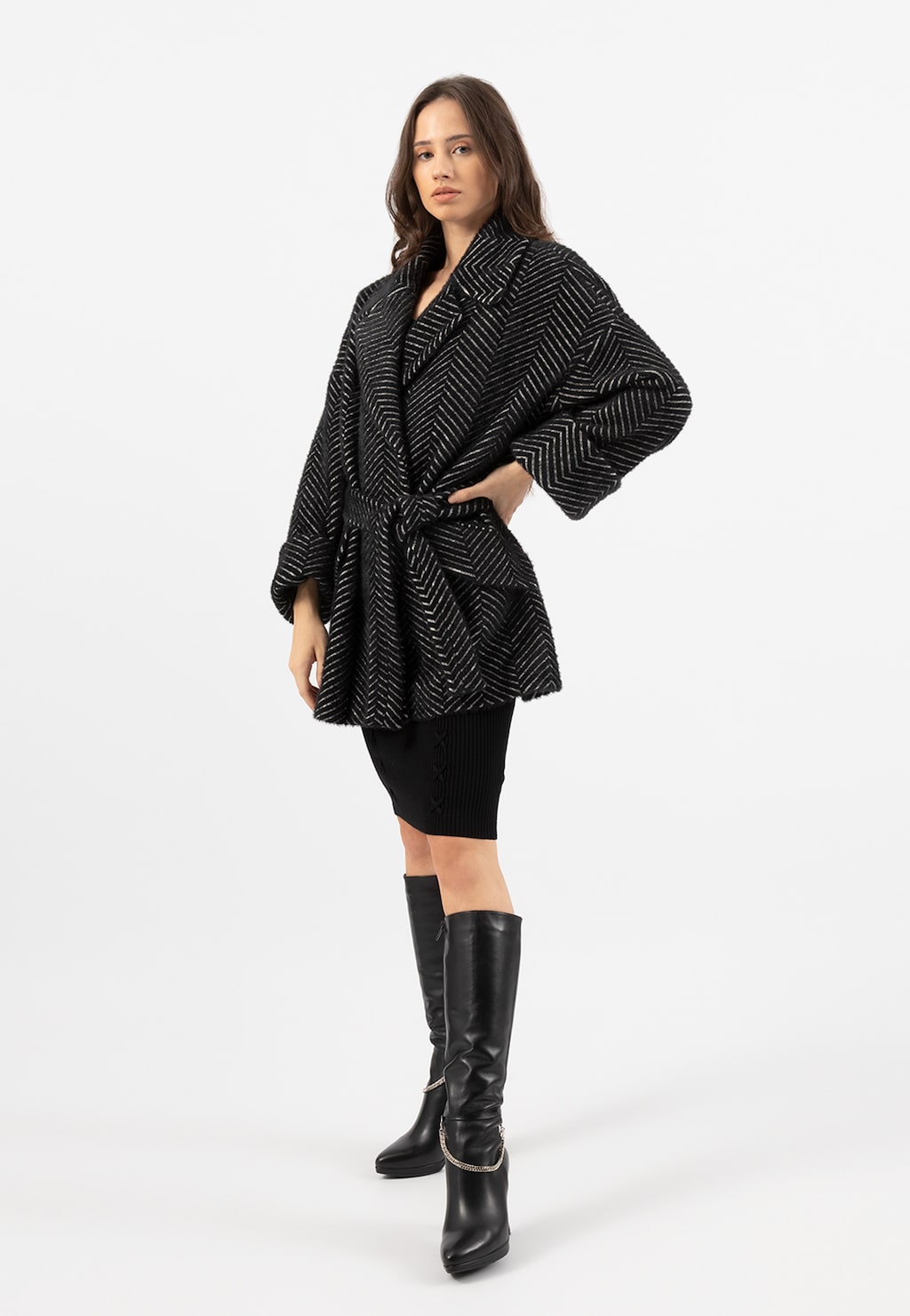 Czarny puchaty płaszcz RELAKS model R9902341 z wzorem jodełki, prezentowany z czarną spódnicą i eleganckimi kozakami. Widok z przodu na całą sylwetkę.