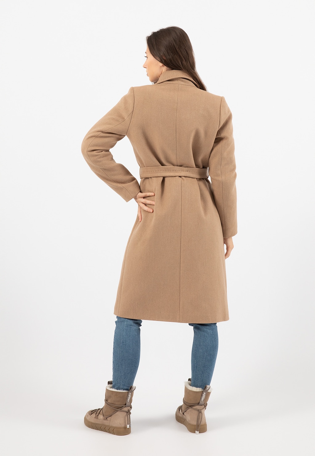 Elegancki beżowy płaszcz damski Relaks R99020-44 widok od tyłu, z paskiem w talii, ukazany na modelce w jeansach i beżowych butach marki Relaks.