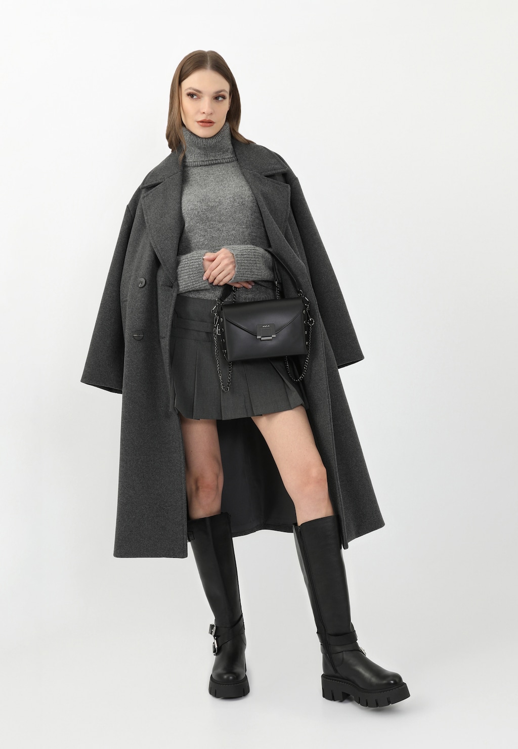 Elegancka stylizacja z czarnymi skórzanymi kozakami Wojas model 71053-51 typu bikery ze srebrnymi klamrami, w połączeniu z szarym płaszczem, golfem i mini spódniczką.