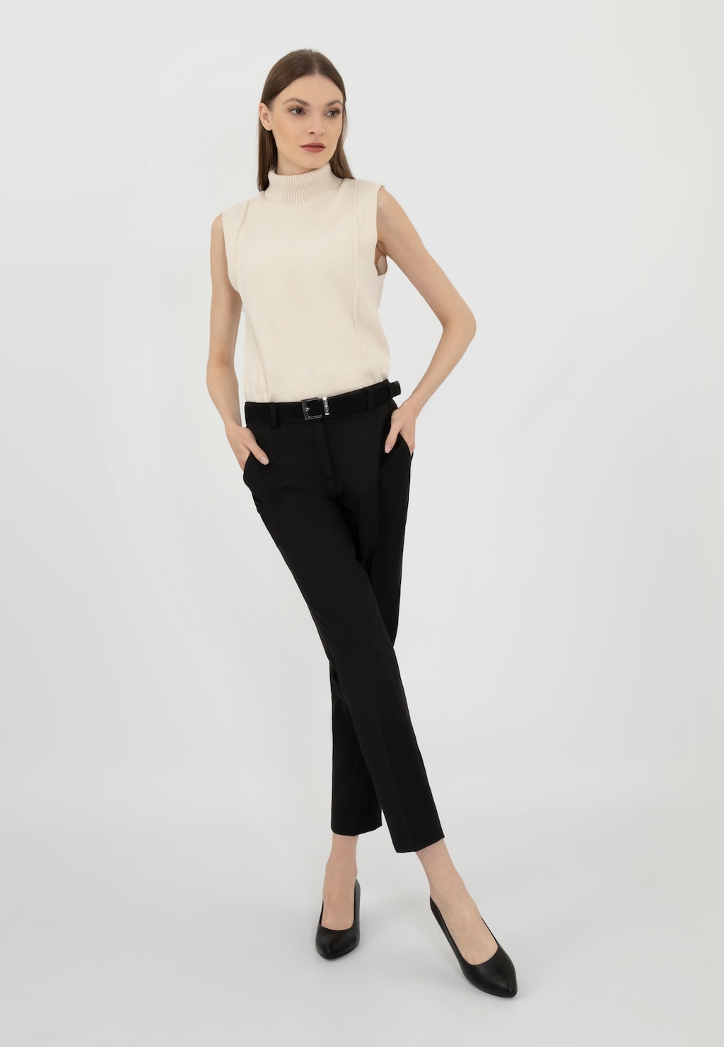 Modelka w eleganckim stroju biznesowym prezentująca czarne czółenka Wojas model 35121-51 ze skóry licowej, widoczne w stylizacji z kremową bluzką bez rękawów i czarnymi spodniami.