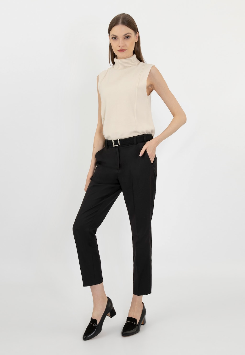 Modelka w eleganckim stroju z kremową bluzką bez rękawów i czarnymi spodniami, prezentująca czarne półbuty damskie Wojas model 46014-71 na niewielkim obcasie.