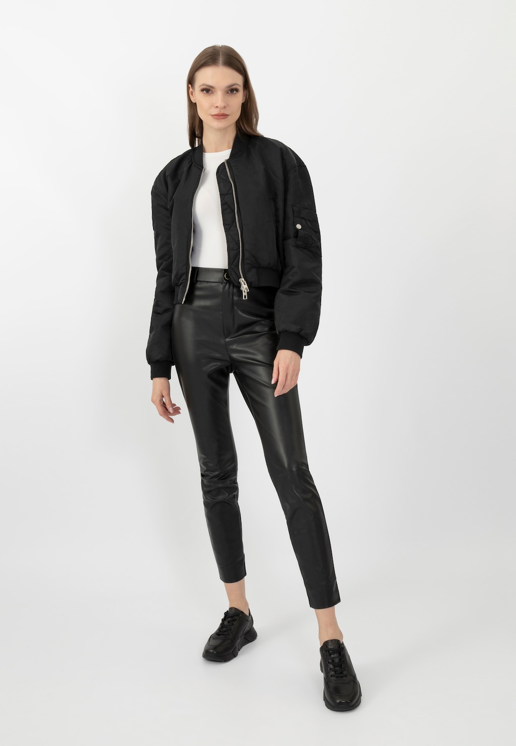 Modelka w czarnej kurtce bomberka, białej bluzce i skórzanych spodniach, prezentująca czarne półbuty damskie Wojas model 9406-51 w nowoczesnej, miejskiej stylizacji.