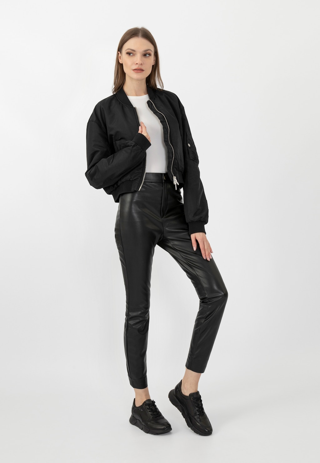 Modelka w czarnej kurtce bombersce, białej bluzce i skórzanych spodniach prezentuje eleganckie czarne półbuty damskie Wojas model 9406-51 w casualowej stylizacji.