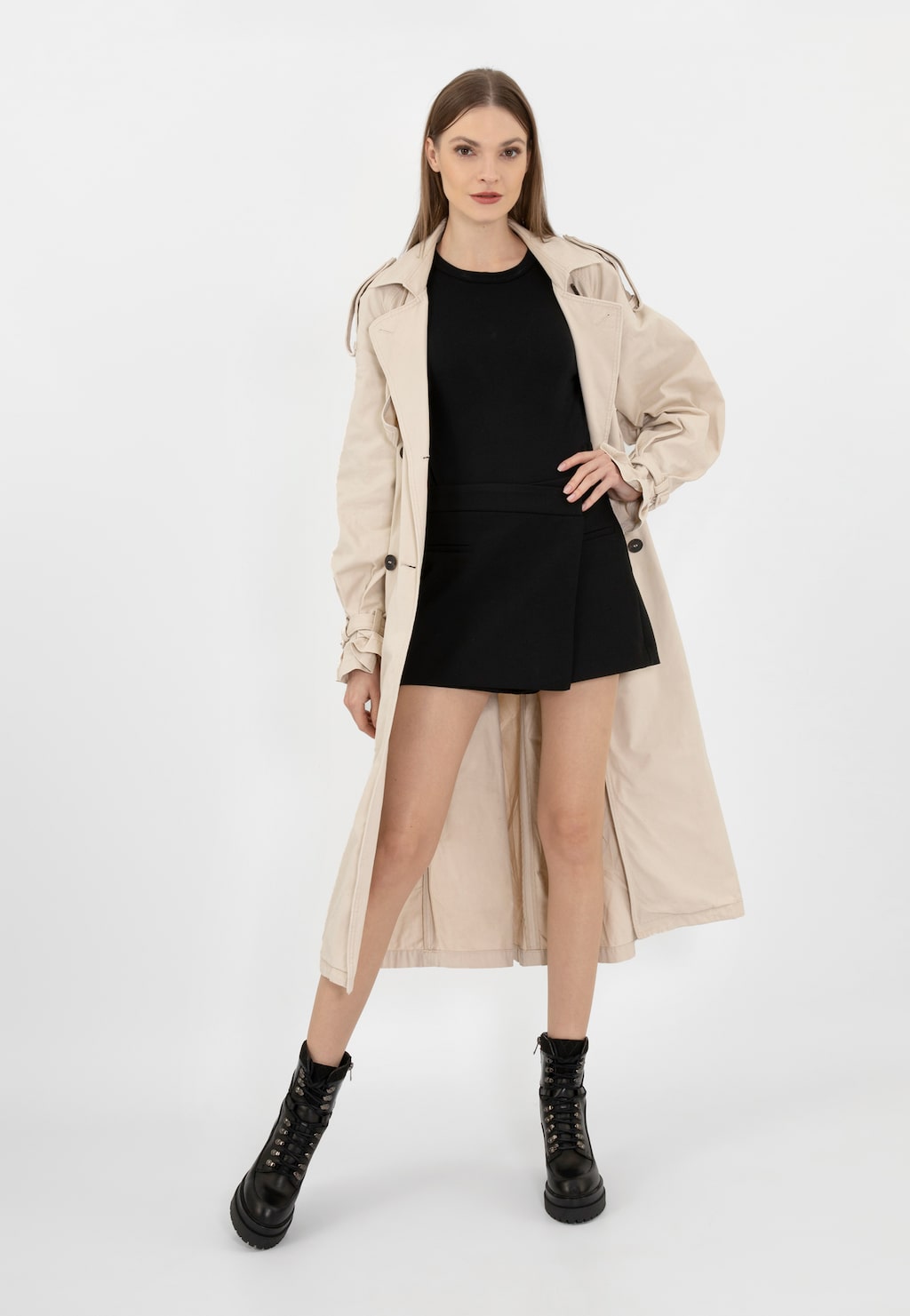 Modelka w beżowym płaszczu i czarnej sukience prezentuje czarne bikery Wojas model 64104-81 - stylowe botki na obcasie wykonane z łączonych skór.