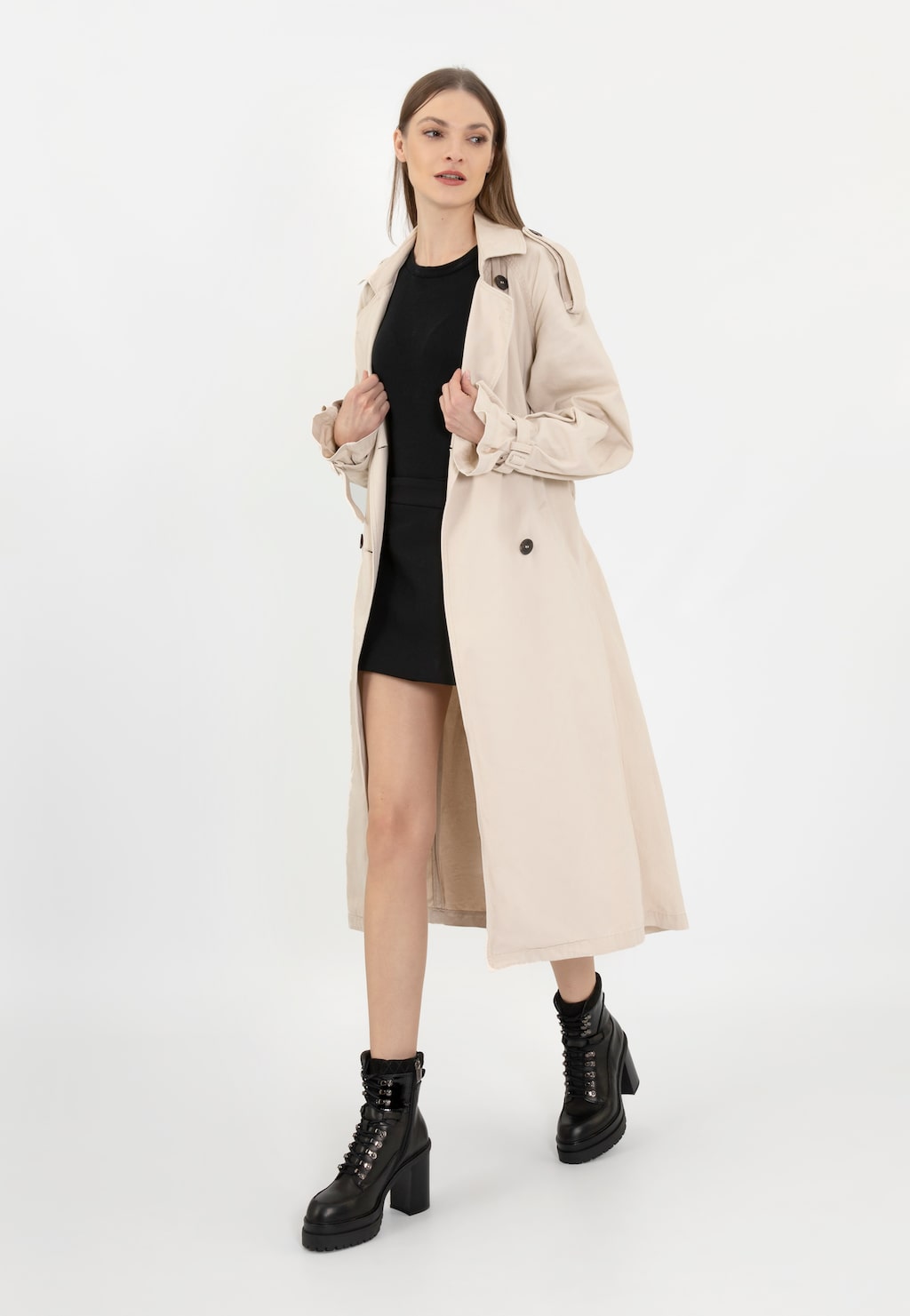 Modelka w beżowym płaszczu i czarnej sukience prezentuje czarne skórzane bikery Wojas model 64104-81 na obcasie, idealne uzupełnienie eleganckiej stylizacji.