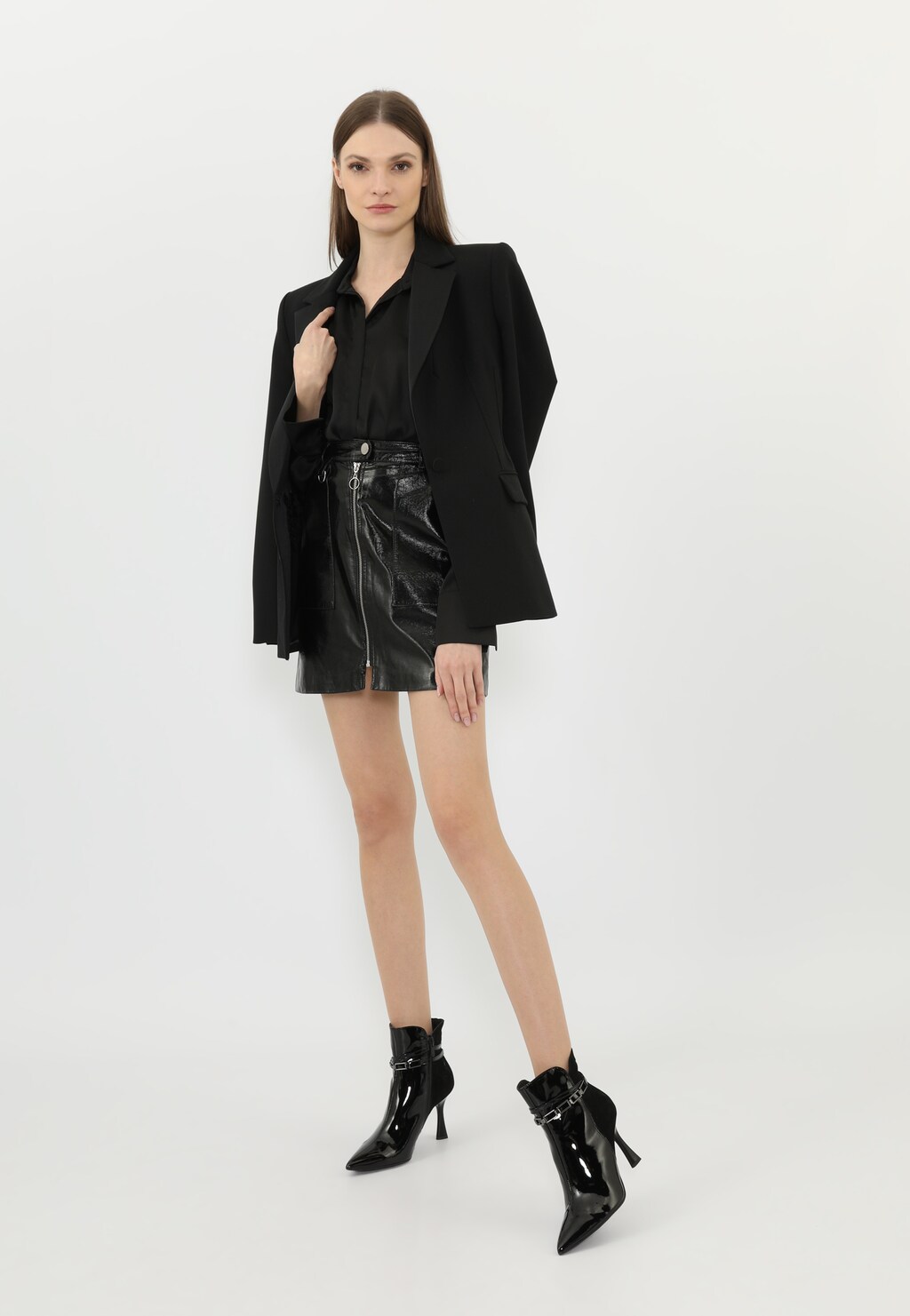 Elegancki czarny strój z czarnymi botkami Wojas model 55209-71, wyróżniającymi się ozdobnym łańcuchem wokół kostki, prezentowany w całej stylizacji ze skórzaną spódnicą i marynarką.