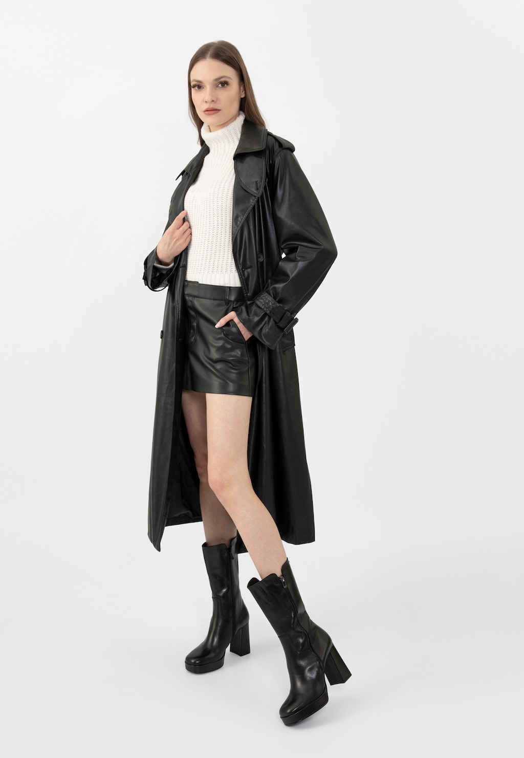 Czarne botki damskie Wojas model 55215-51 na wysokim obcasie eksponowane w stylizacji z długim skórzanym płaszczem, białym golfem i skórzaną minispódniczką.