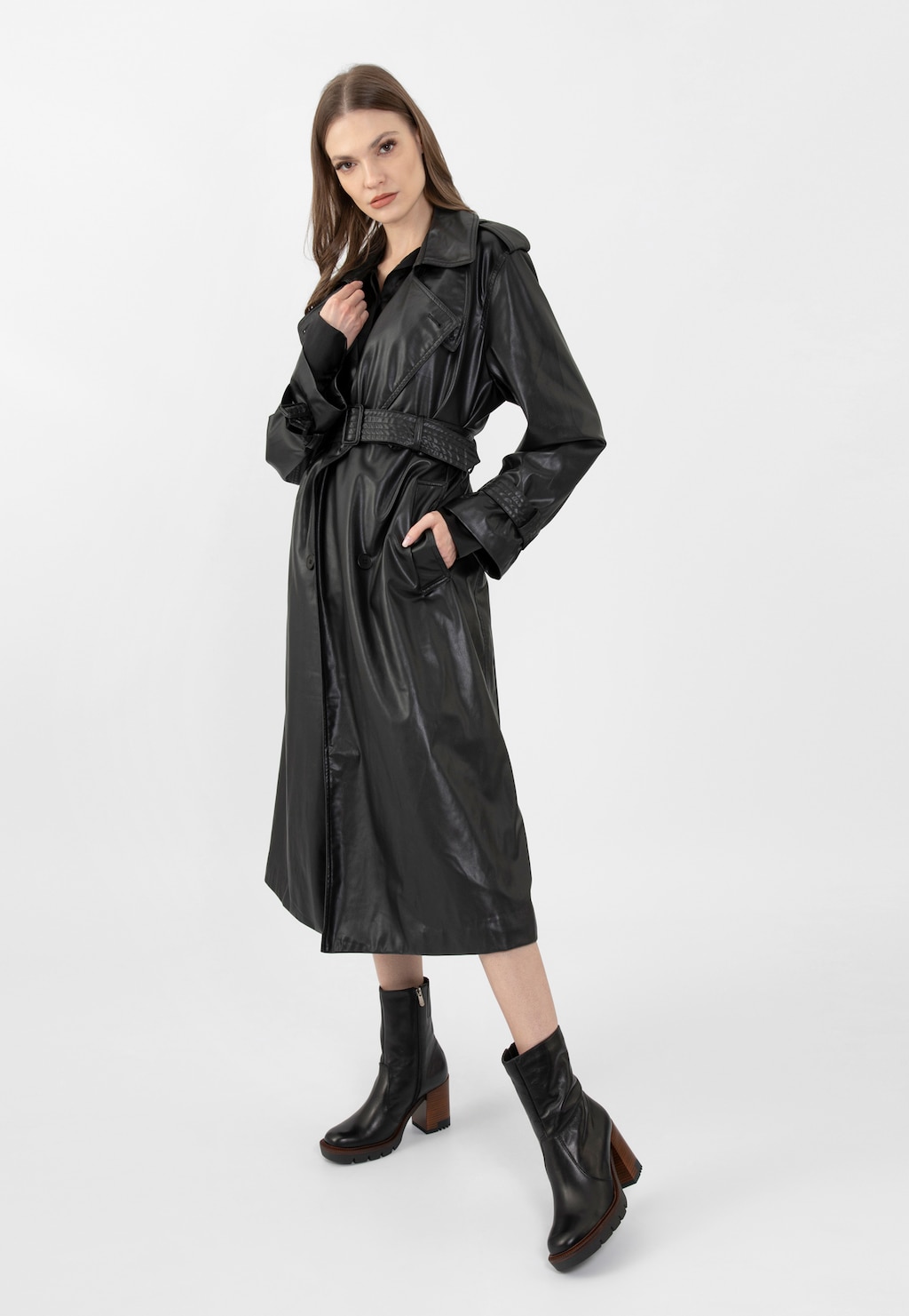 Modelka w czarnym skórzanym płaszczu prezentuje botki damskie Wojas model 55225-51 - czarne z charakterystycznym brązowym obcasem, idealne do eleganckich jesiennych stylizacji.