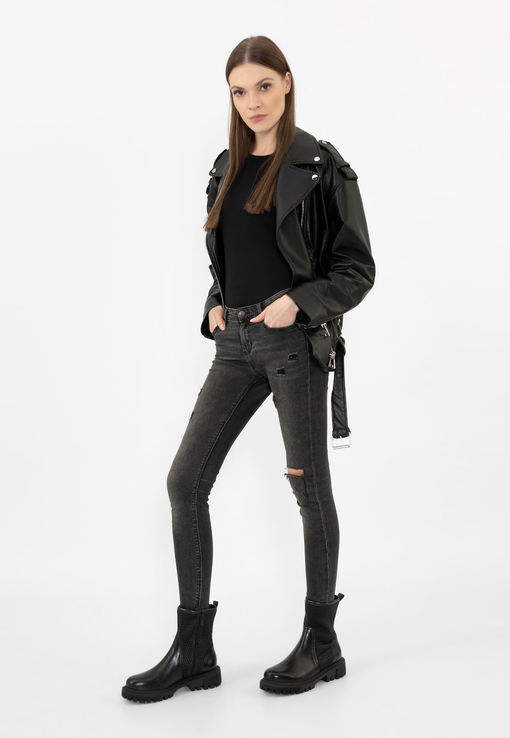 Osoba w czarnej ramonesce i podartych jeansach prezentująca czarne elastyczne botki Wojas model 55228-81 zapinane na zamek, z grubą podeszwą i elastycznymi wstawkami po bokach.