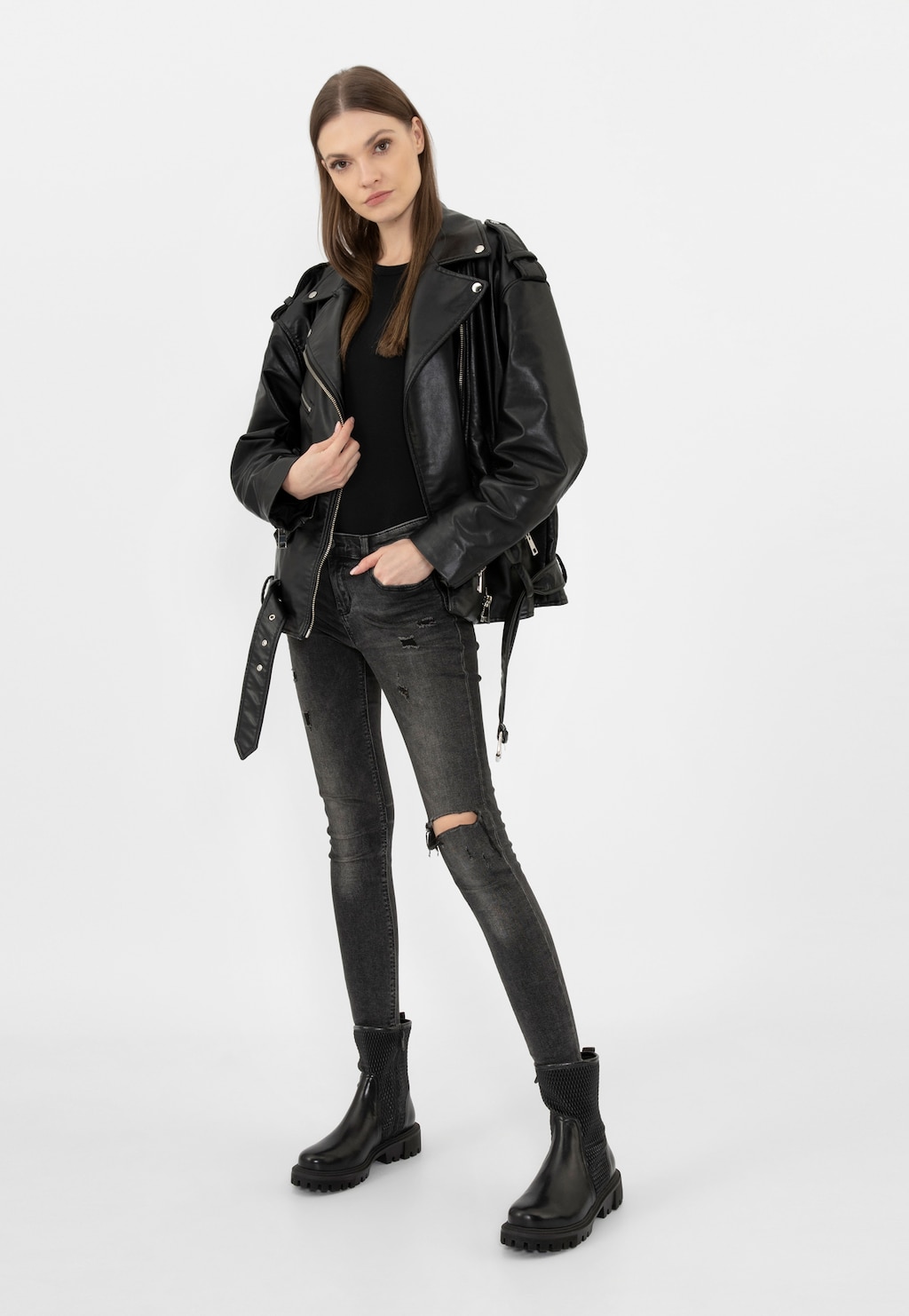 Modelka w czarnej stylizacji prezentująca czarne elastyczne botki damskie Wojas model 55228-81 zapinane na zamek. Buty widoczne w pełnej stylizacji z kurtką i dżinsami.