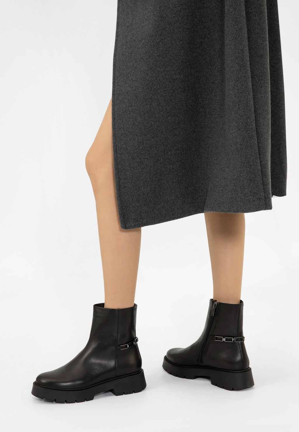 Czarne botki damskie Wojas 55231-51 ze skóry licowej z metalową ozdobą, prezentowane na modelce w szarej spódnicy, z grubą podeszwą i bocznym zamkiem.