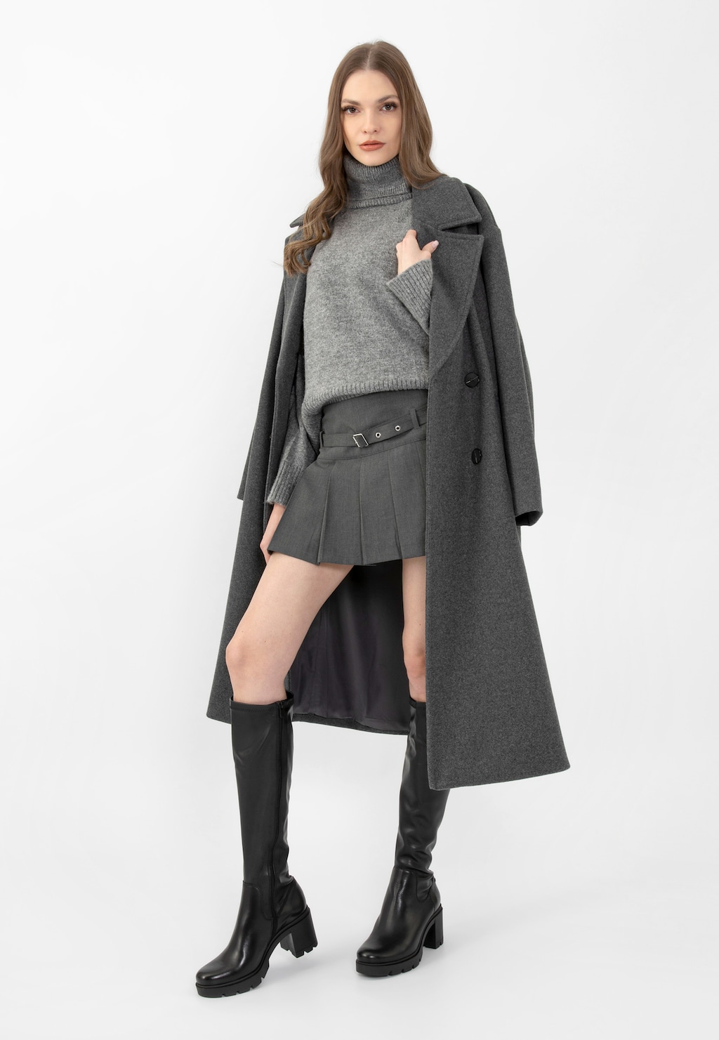 Modelka w szarym płaszczu i golfie, prezentująca czarne skórzane kozaki damskie Wojas 71025-51 na masywnym słupku, zestawione z szarą mini spódniczką.