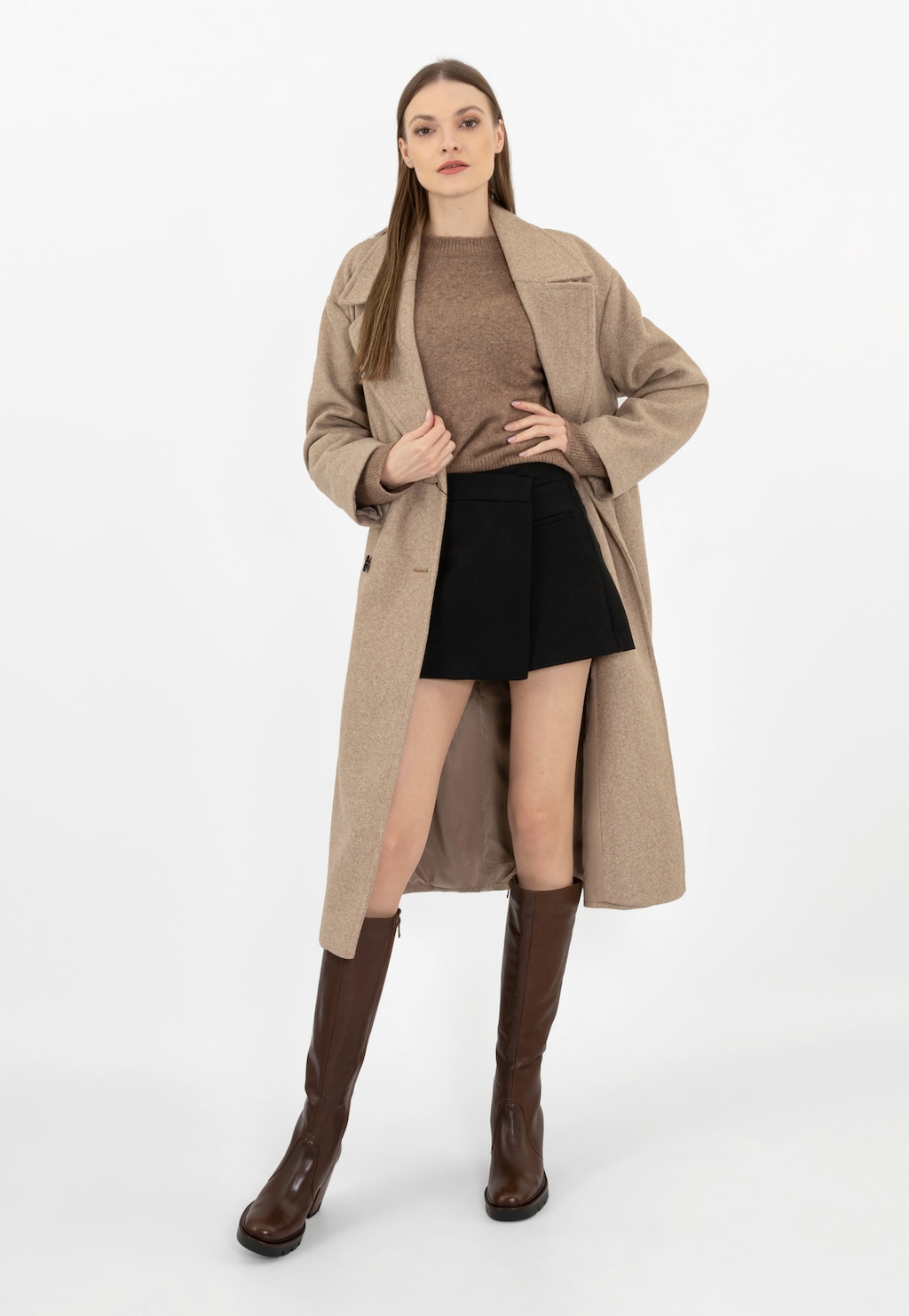 Modelka w beżowym płaszczu i swetrze, czarnej spódnicy oraz brązowych kozakach Wojas ze skóry licowej model 71050-52, prezentujących elegancki jesienno-zimowy styl.