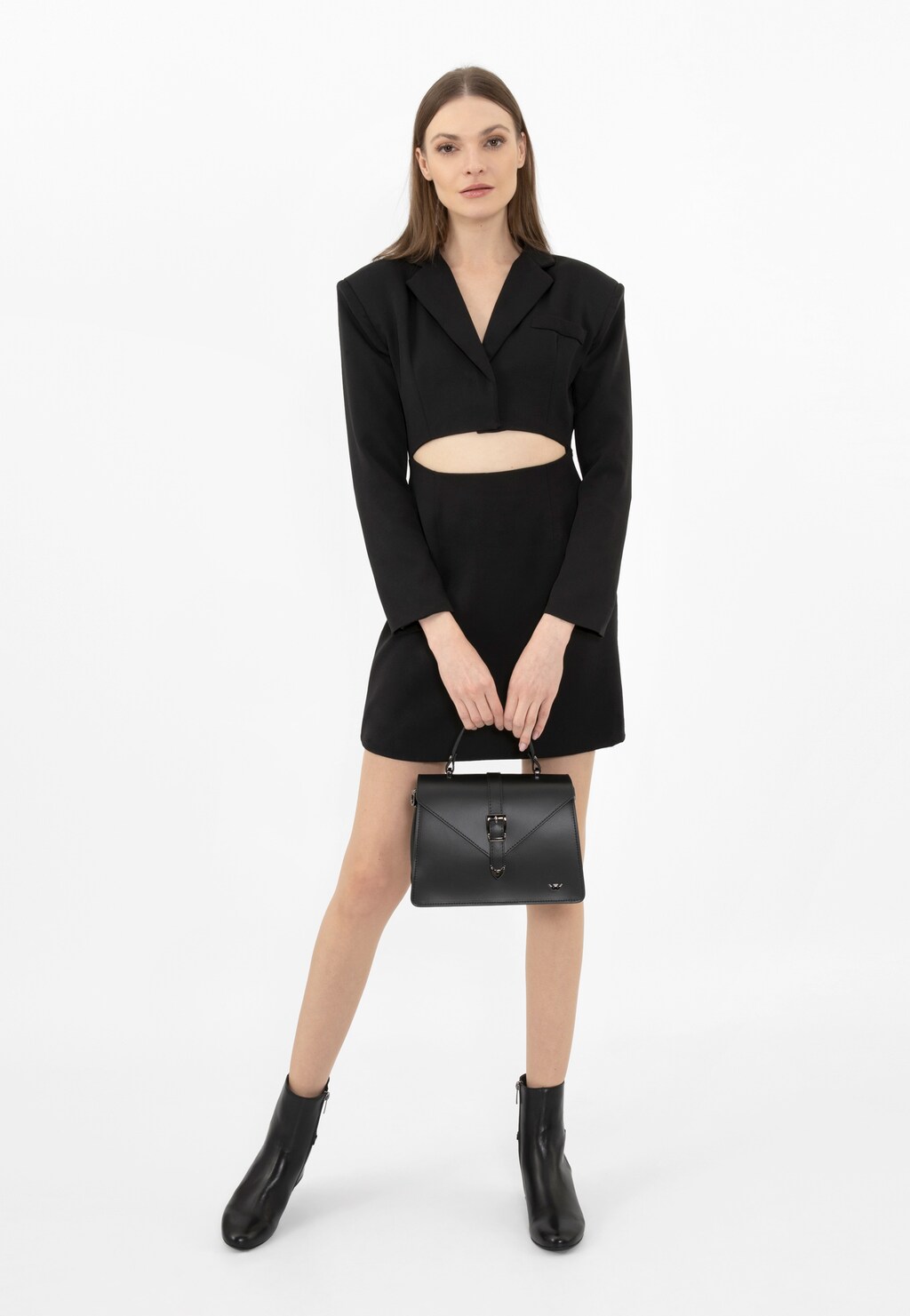Modelka w czarnym komplecie trzymająca elegancką czarną skórzaną torebkę kuferek Wojas model 80337-51, uzupełniając stylizację butami marki Wojas.