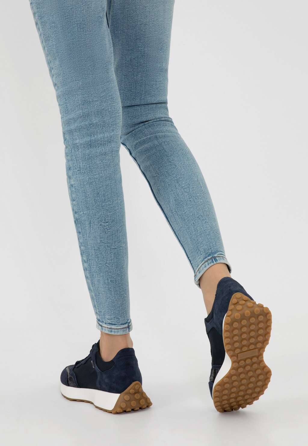 Granatowe sneakersy damskie Wojas model 46245-86 z łączonych materiałów, widoczne z tyłu na nogach w jasnych jeansach, z charakterystyczną gumową podeszwą.