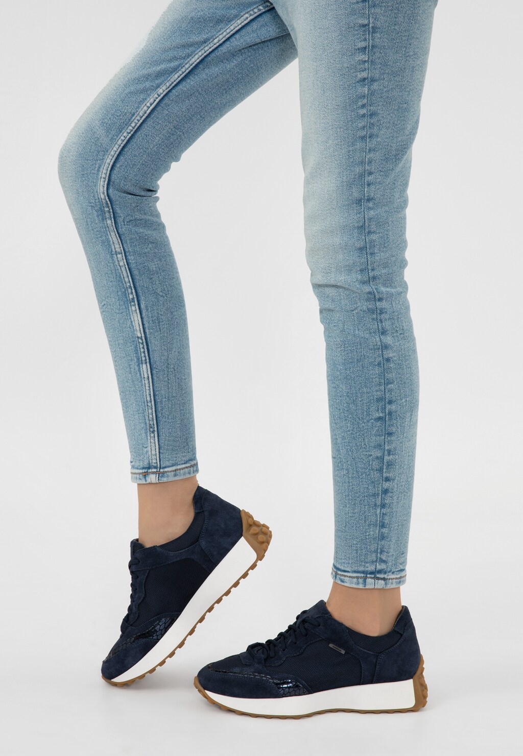 Granatowe sneakersy damskie Wojas model 46245-86 z łączonych materiałów na białej podeszwie z gumowym spodem, noszone z jasnymi jeansami.