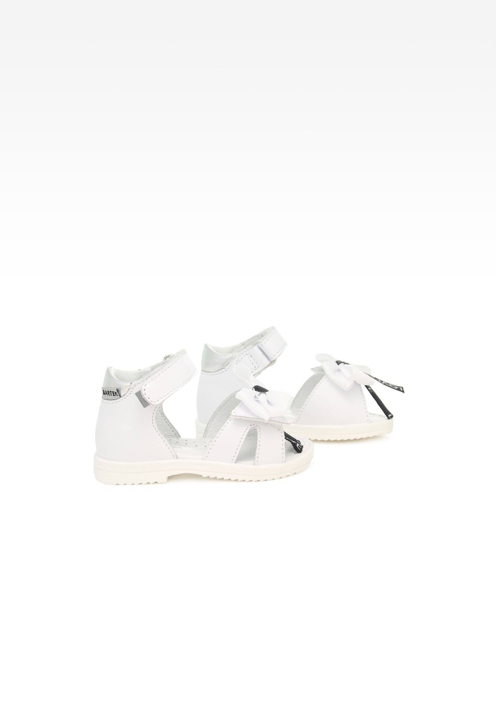 Białe sandały dziewczęce Bartek 11534002 z ozdobnymi kokardkami, zapinane na rzep, widok z boku. Eleganckie obuwie dziecięce na jasnej podeszwie.
