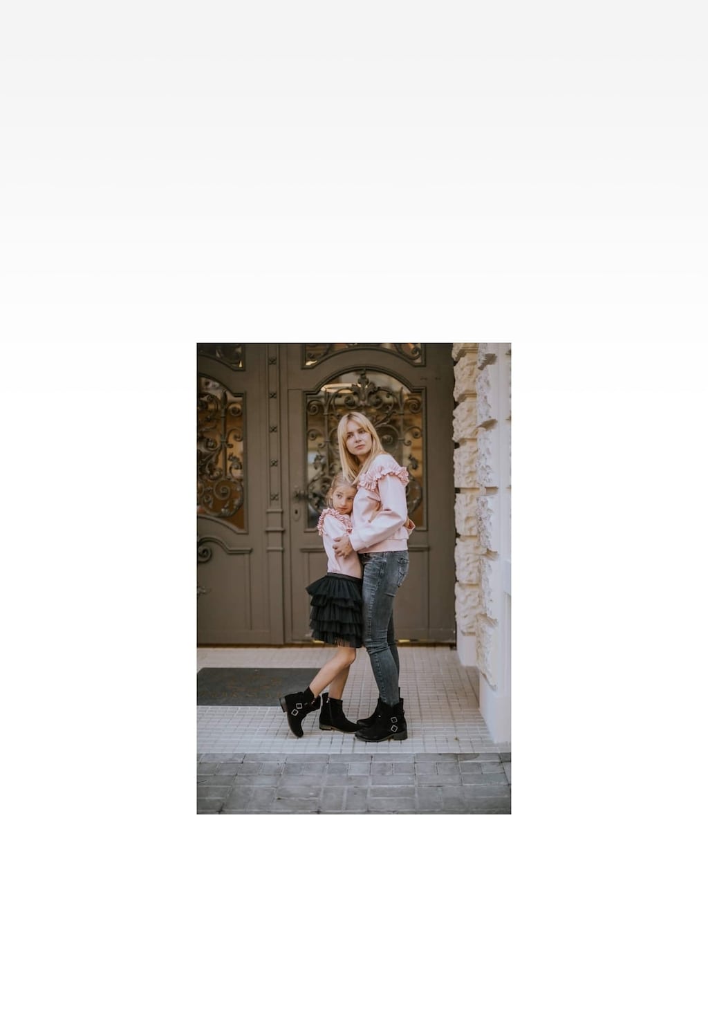 Stylowe czarne botki dziecięce Wojas x Bartek 8440461 dla dziewcząt prezentowane na nogach przed ozdobnymi drzwiami wejściowymi, idealne do codziennych stylizacji.