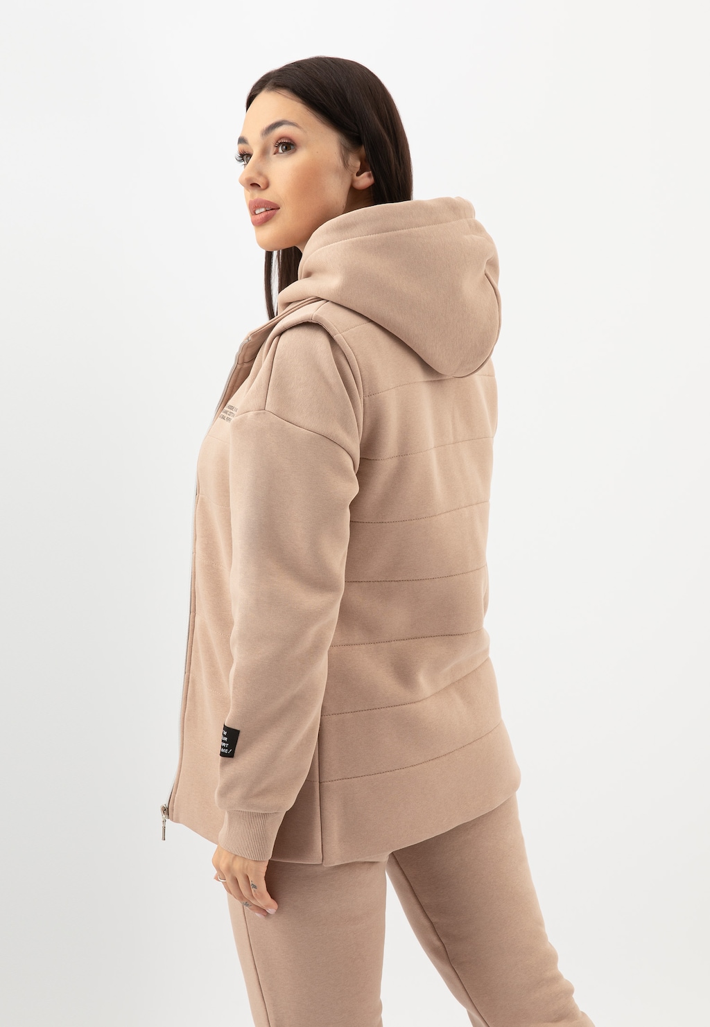 Beżowa kamizelka dresowa Relaks model R98020-14 z kapturem, prezentowana z profilu, podkreślająca sportowy, casualowy styl, z widocznym pikowanym tyłem.