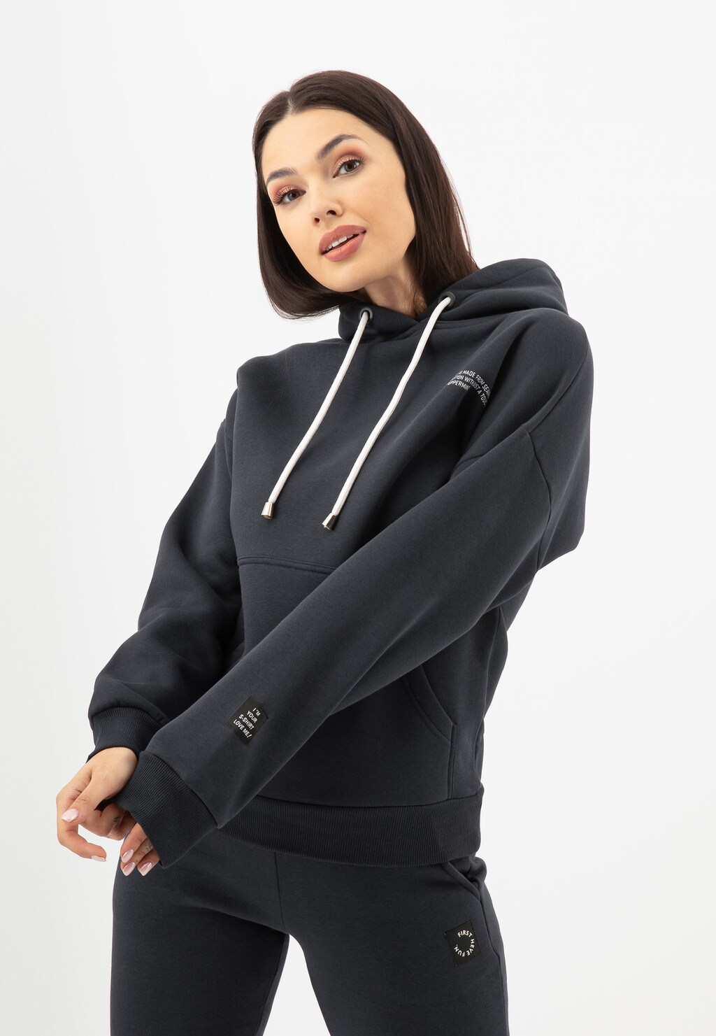 Bluza damska RELAKS model R98010-11 w kolorze ciemnego popielu z kapturem i białymi sznurkami, prezentowana na modelce w kompletnym dresowym zestawie.