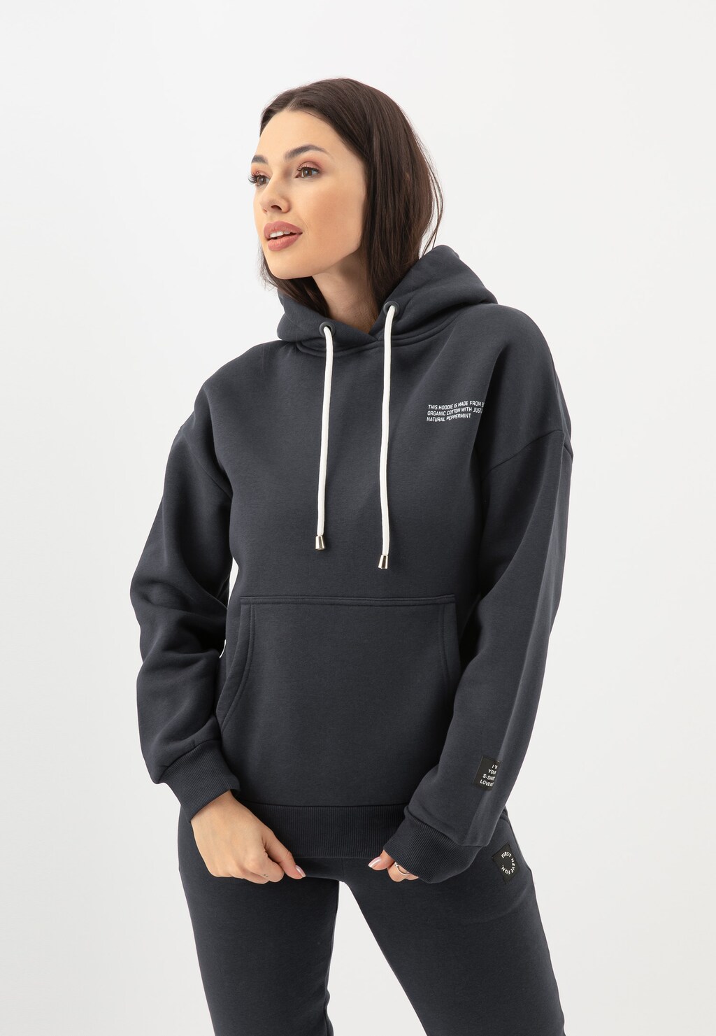 Bluza damska RELAKS model R98010-11 w kolorze ciemnego popielu z kapturem i kieszenią kangurką, prezentowana na modelce w sportowej stylizacji.