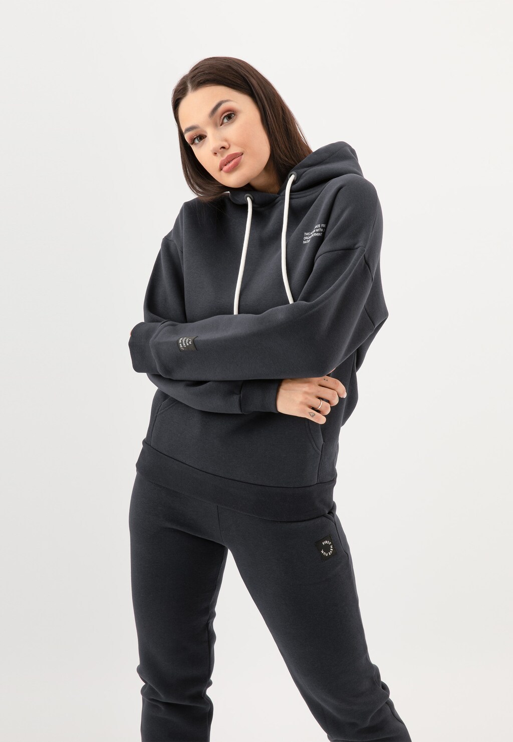 Bluza damska RELAKS model R98010-11 w kolorze ciemnego popielu z kapturem i białymi sznurkami, prezentowana w komplecie ze spodniami dresowymi tej samej marki.